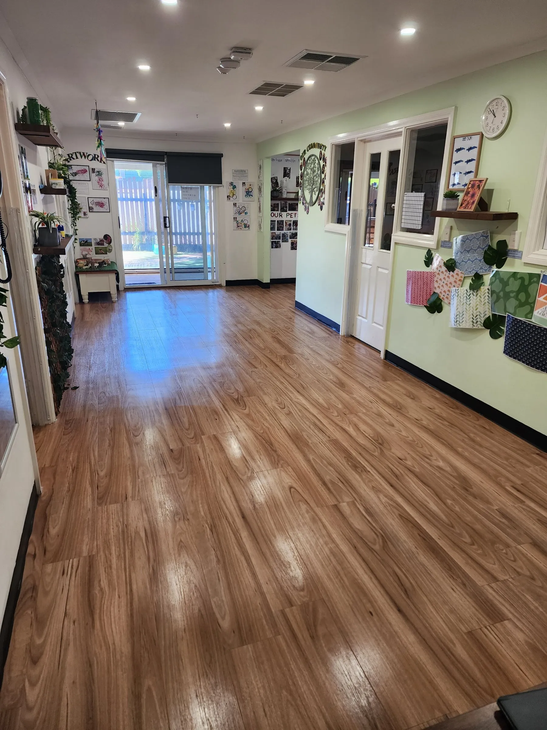Bright room with a polished timber-look floor and children's shelving