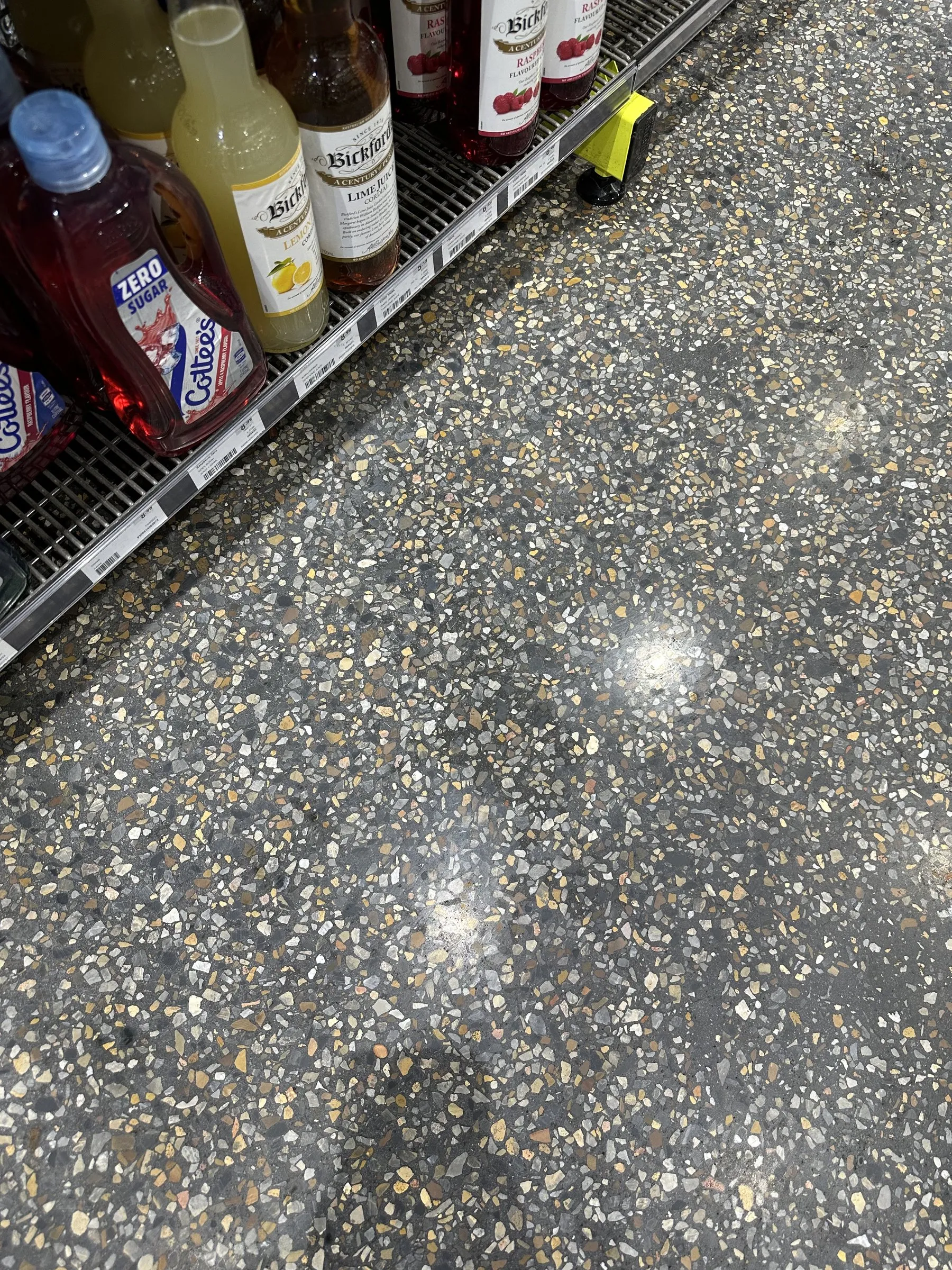 Close-up of polished aggregate concrete in a food store, sauce bottles on a shelf