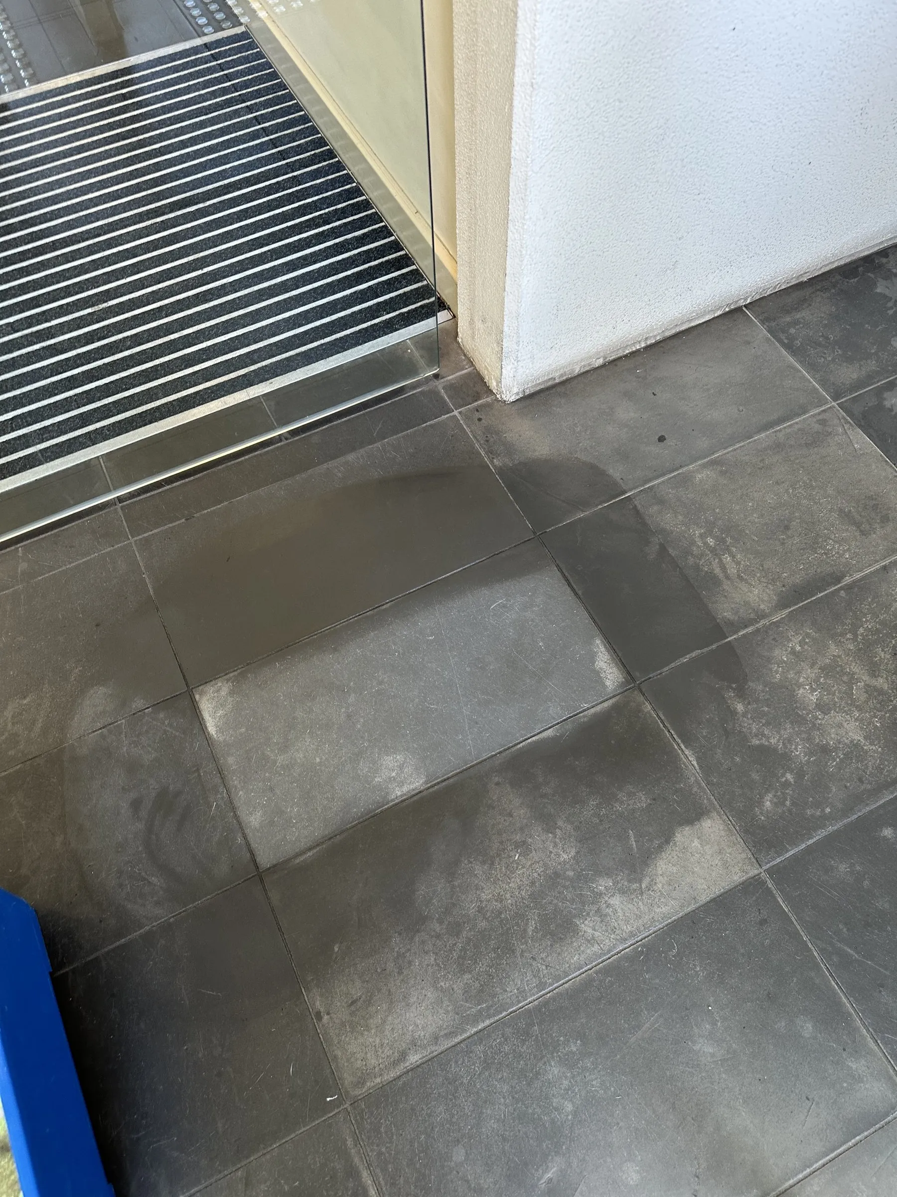 Dark grey floor tiles beside a recessed entry mat
