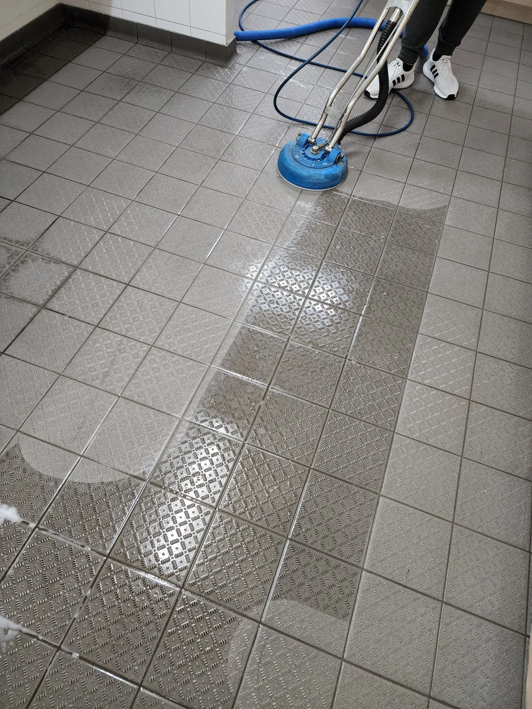 Spinner wand on grey textured floor tiles, half cleaned