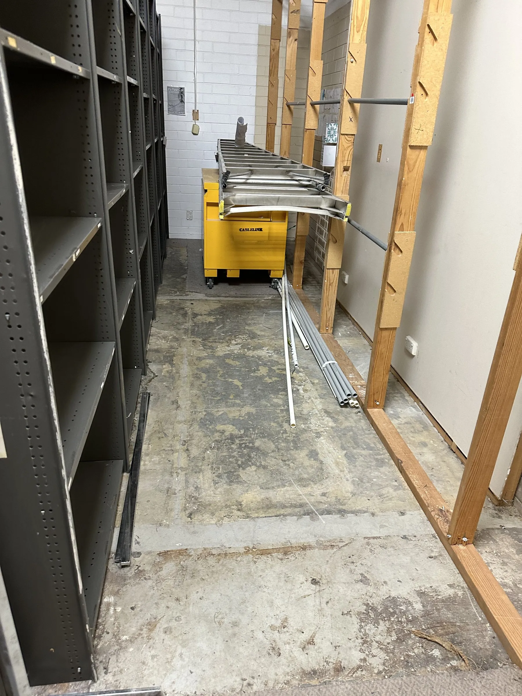 Storeroom with steel shelving and a dusty concrete floor, before cleaning